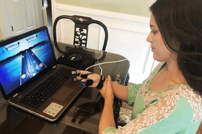 woman with brain injury using MusicGlove video game for TBI