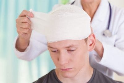Doctor bandaging head of man with focal brain injuries