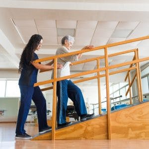 physiotherapist helping woman with rehab exercises to walk again