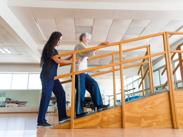 physiotherapist helping woman with rehab exercises to walk again