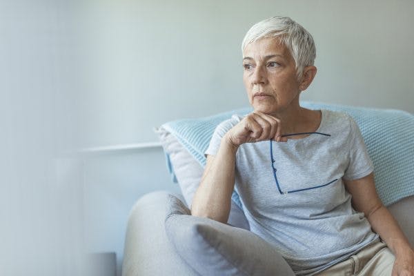 senior woman looking out window, absorbed in thought because she has anxiety after stroke