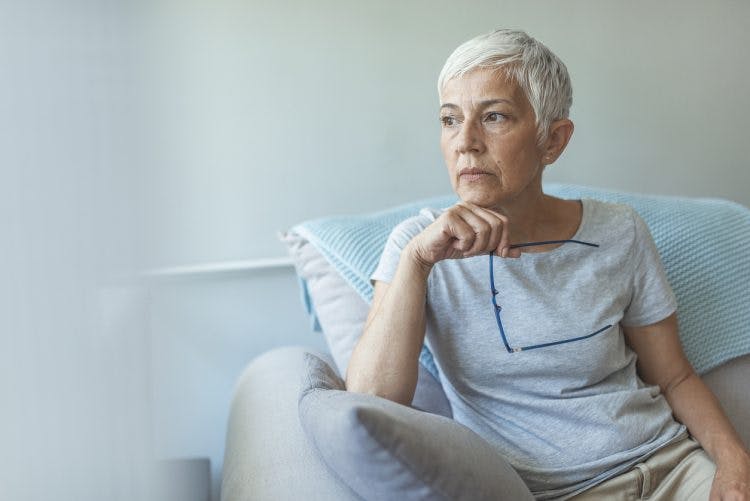 senior woman looking out window, absorbed in thought because she has anxiety after stroke