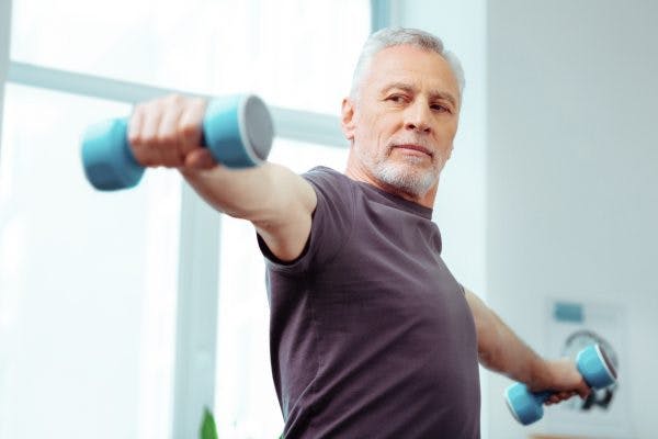 strong elderly man lifting dumbbells because he experienced spontaneous recovery after stroke
