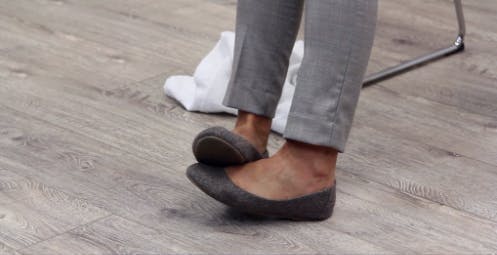 Therapeutin zeigt Fußtropfenübungen, indem sie ihren Fuß mit dem anderen Fuß anhebt