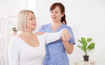 therapist moving patients arm as part of her sensory stimulation activities for TBI