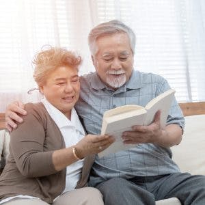 elderly married couple reading a stroke book together on a sofa