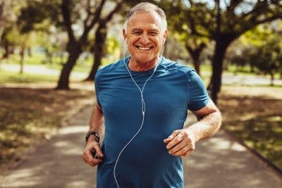 senior man smiling and jogging in park 