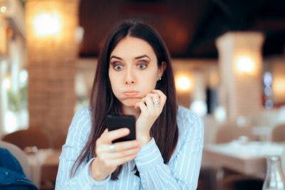 Woman looking at smartphone with surprise from inappropriate behavior