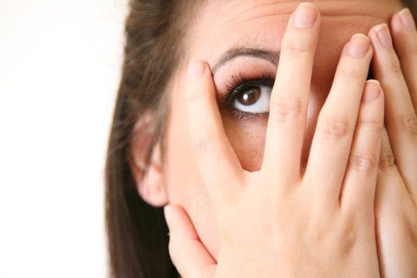 woman with left visual field cuts covering right eye and peeking out from left hand