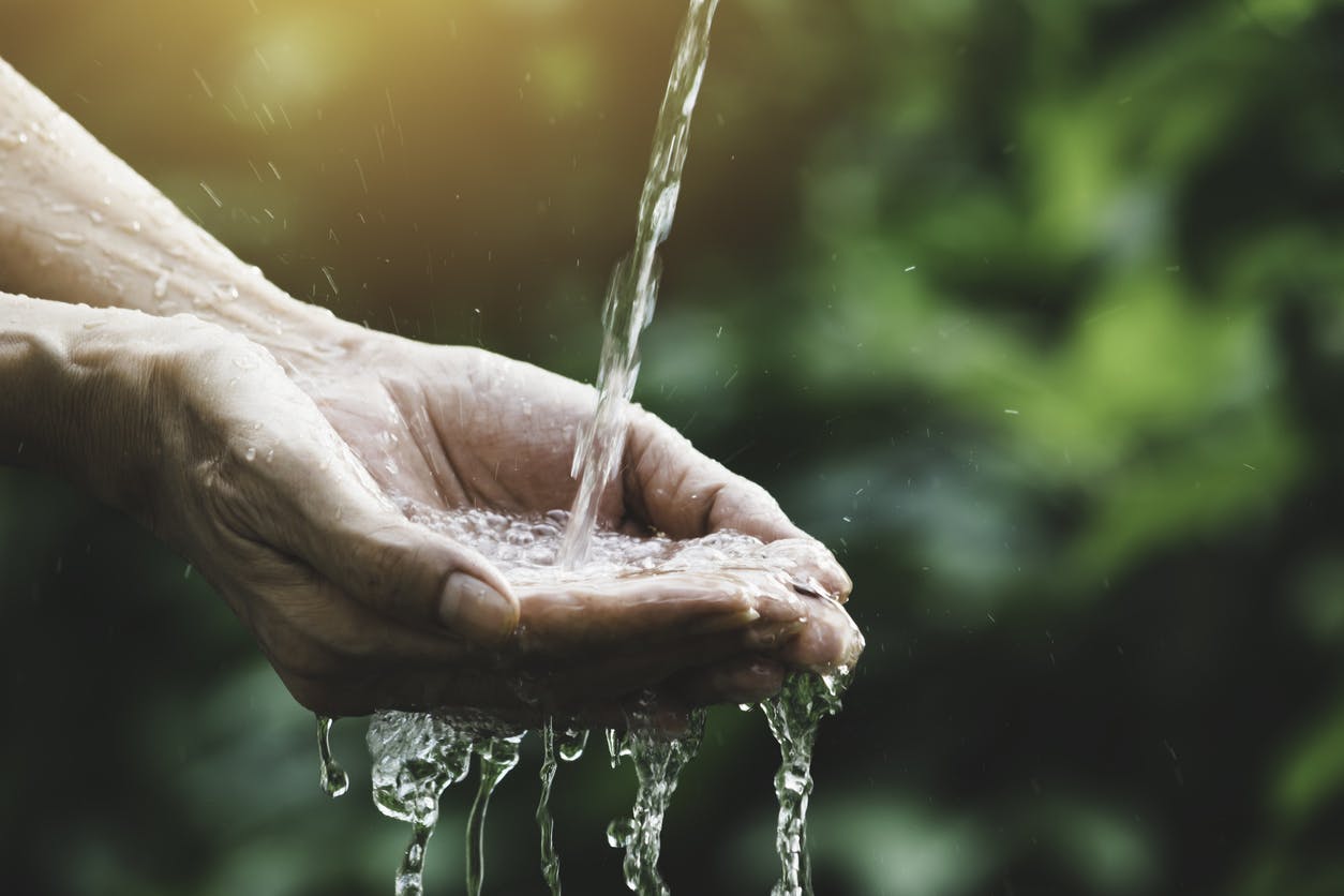 closeup water flow to hand of women for nature concept on the garden background to represent another sensory stimulation activity for TBI