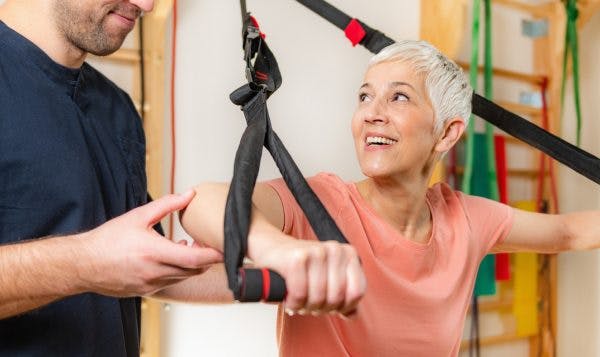 senior woman training on TRX as part of her acquired brain injury treatment