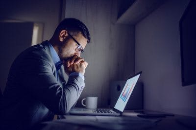 man staring at laptop late at night because he has perseveration after brain injury