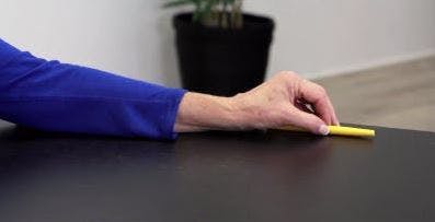 Therapeut bewegt Stift über Tisch für Handübung