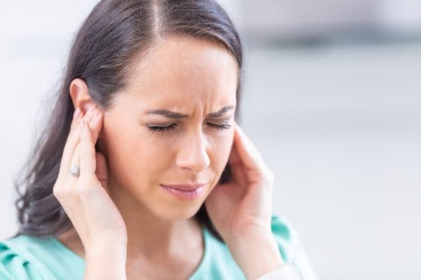 woman grimacing and rubbing her because she has tinnitus after head injury