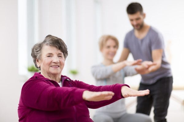 Elderly woman smiling at camera doing exercises to help with TBI recovery