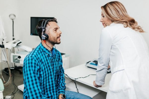 audiologist performing a hearing test on survivor in order to diagnose tinnitus after head injury