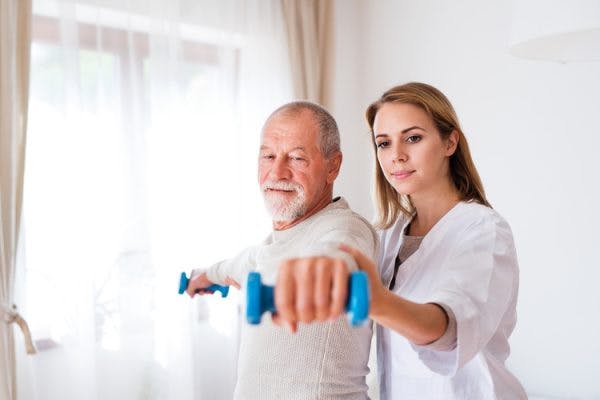 Therapist helping stroke patient lift dumbbells to overcome the effects of a stroke in the motor cortex