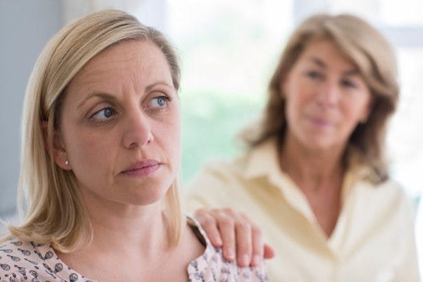 Mother putting hand on adult daughter's shoulder who has personality changes after head injury