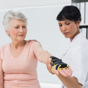Doctor helping stroke patient try on different types of gloves for stroke patients