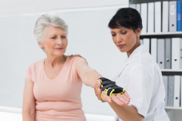 Doctor helping stroke patient try on different types of gloves for stroke patients