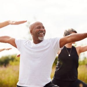Senior man doing group yoga in park to promote a successful mini-stroke recovery