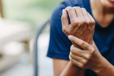 Woman rubbing stiff wrist because she has spasticity after TBI