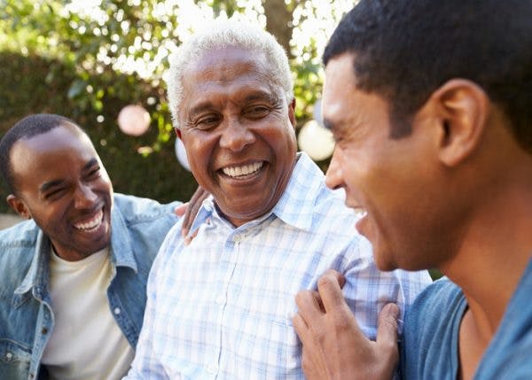 Two adult sons laughing with elderly dad who had a stroke