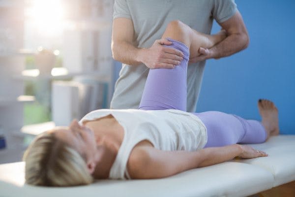 Therapist stretching woman's knee to treat her spasticity after TBI