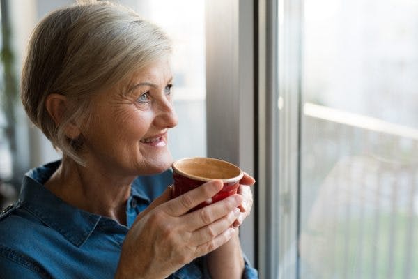 Stroke survivor holding coffee cup and looking out window