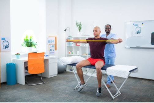 occupational therapist helping stroke survivor with resistance training exercise