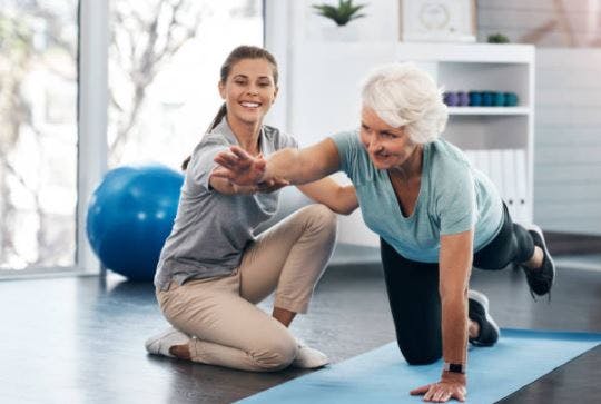 physical therapist helping elderly stroke survivors with active exercise from a quadruped position