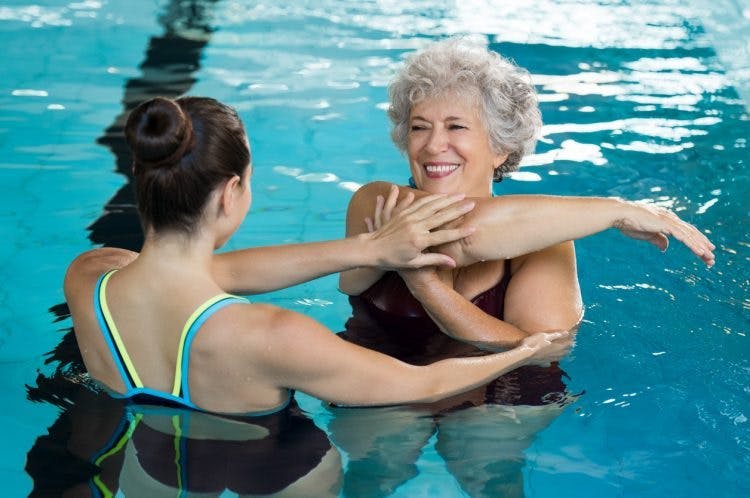 spinal cord injury patient practicing aquatic therapy exercises with PT
