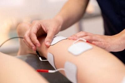 therapist using electrical stimulation on stroke patient's legs