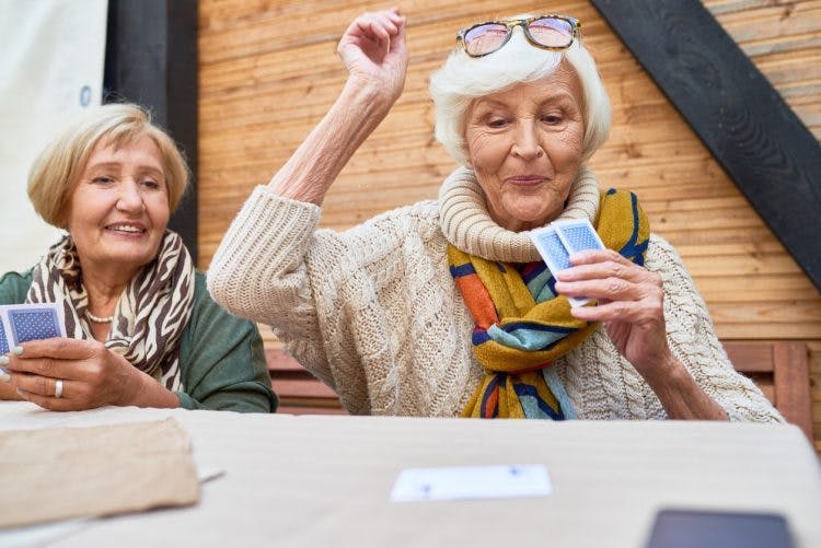 glückliche Frau, die beim Kartenspiel für kognitive Therapie nach Schlaganfall gewinnt