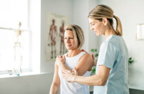 physical therapist helping stroke survivor with passive exercise by moving her arm