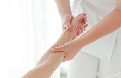 therapist holding stroke patient's swollen arm for passive exercise
