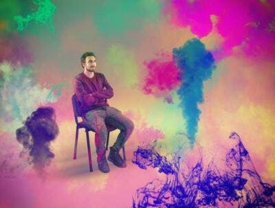 brain injury patient sitting in a chair surrounded by colorful paint to symbolize vivid imagery