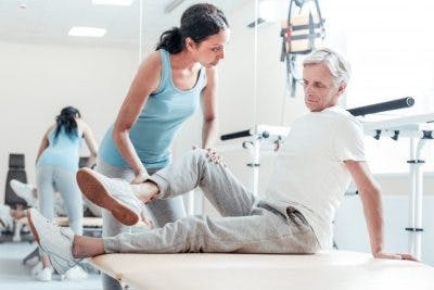 Therapist helping patient sit on exercise bench