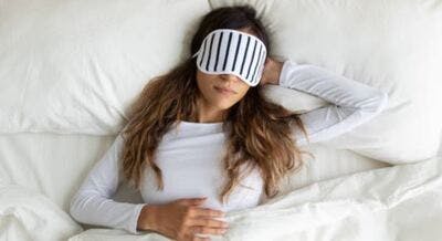 woman sleeping in bed with eye mask on for deep rest