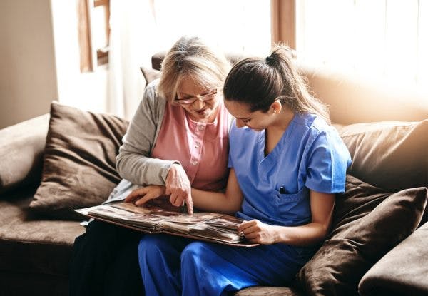 nurse looking through photo album with brain injury patient with dementia