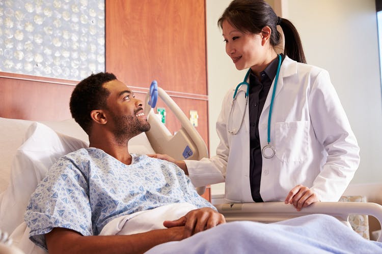 Doctor explaining types of traumatic brain injury to patient in hospital bed