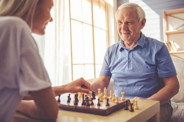 Grandfather and granddaughter playing chess, one of the best games for stroke patients
