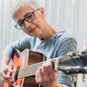 Senior woman playing guitar as part of her TBI music therapy program
