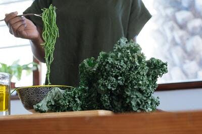 woman eating spinach pasta and kale