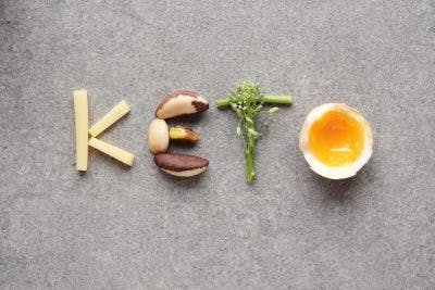 healthy foods arranged to spell "keto" over a gray background