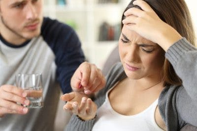 concerned husband handing wife pill to help her headaches after brain injury