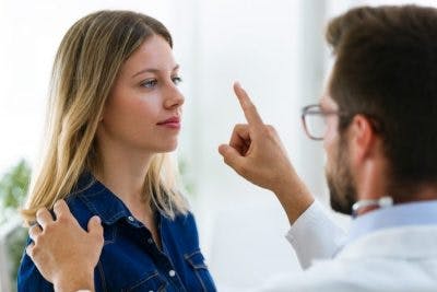 doctor holding finger up in front of woman's eyes to check if vision problems are causing her dizziness after head injury