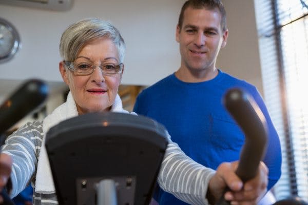 therapist instructing stroke patient on how to use an exercise bike to overcome chronic stroke