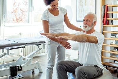 Une physiothérapeute aide un patient atteint d'AVC à effectuer les exercices de rééducation.