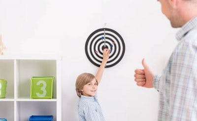 boy with cerebral palsy playing darts with parent